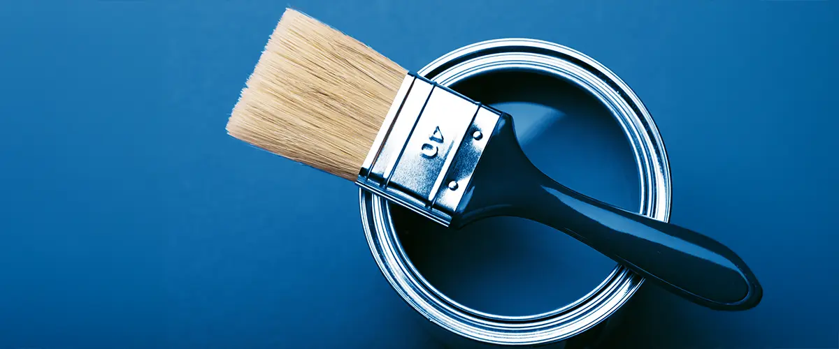 Close-up of a paintbrush resting on an open can of blue paint, ideal for home painting projects.