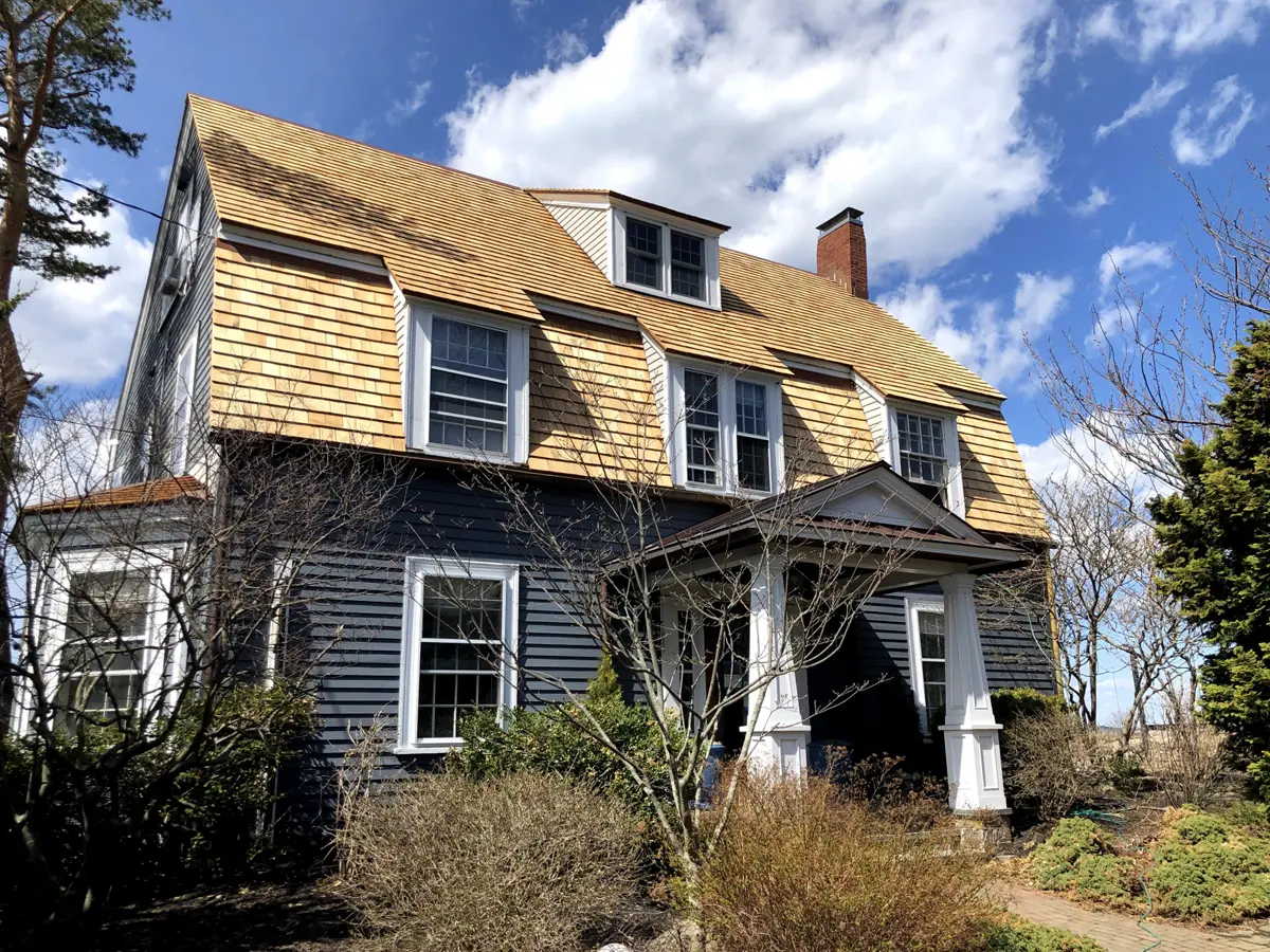 Charming historic home with dark blue siding and new wooden shingle roofing.