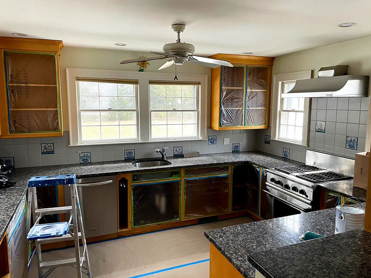 Prepped kitchen for cabinet painting, countertops and floors covered to prevent paint splatters.