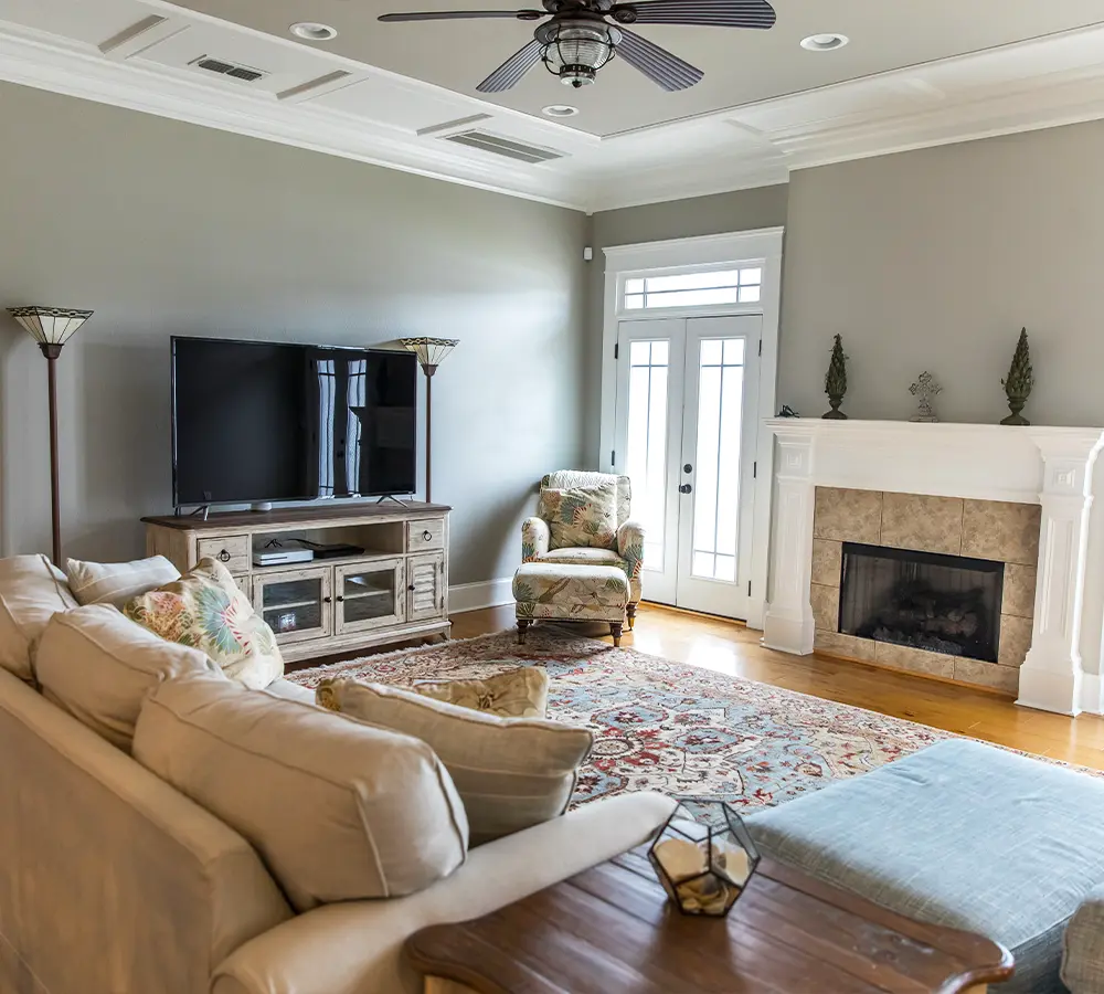 Modern living room with neutral walls, cozy furniture, a fireplace, and a large TV setup.