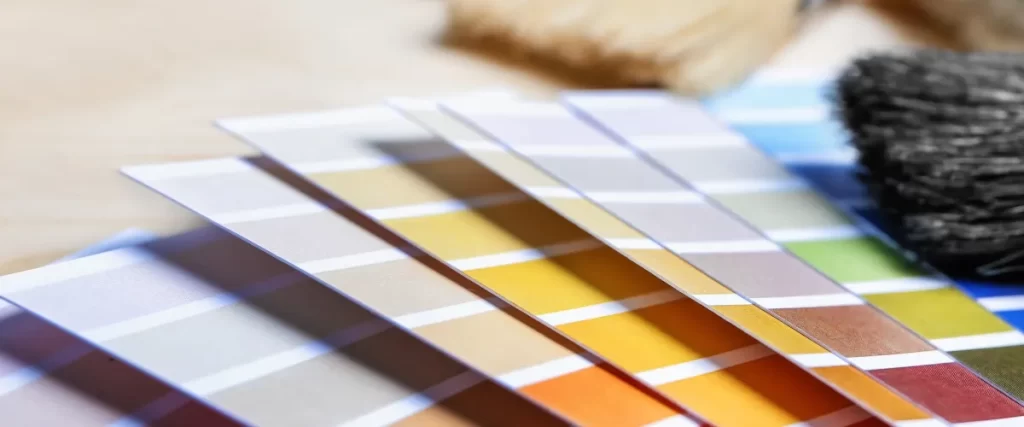 Close-up of paint color samples arranged in a gradient with a paintbrush nearby.