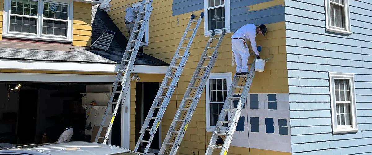 Professional painters on ladders painting a house exterior in Cornelius